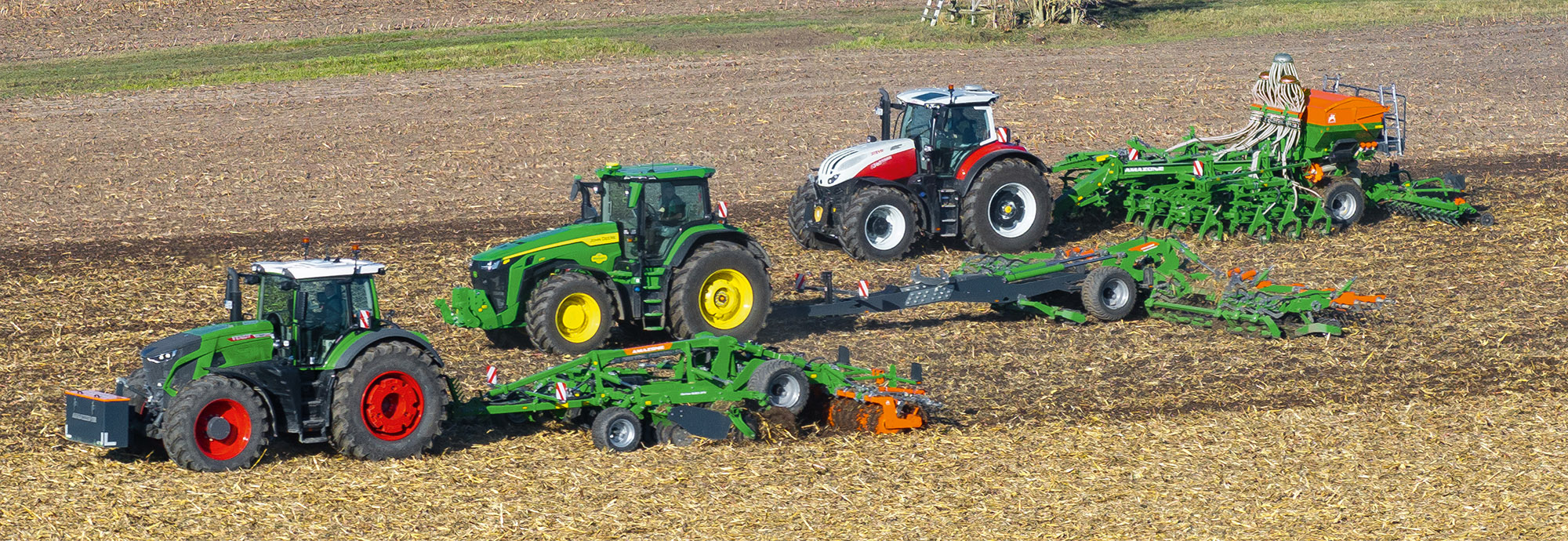 TopCut pour la préparation du lit de semis : Le Certos incorpore en profondeur la paille de maïs grain ; la couche supérieure du sol grossière et motteuse est ensuite travaillée par le combiné de rouleau hacheur TopCut en un lit de terre fine pour le semis, ici avec le Primera DMC. (© AMAZONE : TopCut12000-2T_JohnDeere_PrimeraDMC6000-2C_Steyr_Certos5002-2TX_Femdt_d0_kw_DJI_20241015152355_0451_d1_250821_GO.jpg) TopCut zur Saatbettbereitung: Der Certos mischt das Körnermaisstroh tief ein, der grobe und klutige Oberboden wird anschließend durch die Schneidwalzenkombination TopCut zu einem feinen Saa